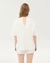 Remera oversize blanca de corte amplio, con cuello redondo y mangas cortas de hombros caídos.