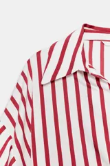 Camisa de corte oversize con estampado de rayas verticales rojas y blancas. Presenta cuello solapa, escote en pico y mangas largas abullonadas con puños elásticos.