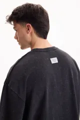 Remera oversize gris oscuro con efecto lavado, cuello redondo y mangas cortas amplias.