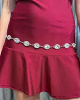 Cinturón tipo caderín de cadena plateada con eslabones ovalados decorados con cristales engarzados.