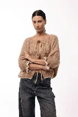 Saco de punto gris con frente abierto y cierre mediante lazos frontales. Presenta mangas abullonadas con puños elásticos y un diseño de textura voluminosa.