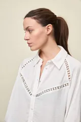 Camisa negra de calce relajado, con mangas 3/4, cuello clásico y cierre frontal con botones. Presenta detalles calados en la parte superior.
