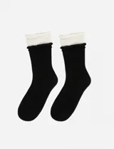 Medias de caña media con diseño de doble capa que simula llevar dos pares, presentando un volado en el borde superior. El cuerpo de la media es negro y el detalle del borde es de color natural.