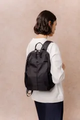 Mochila compacta de color beige, con compartimento principal con cierre, bolsillos laterales y bolsillo frontal con cierre oculto. Cuenta con correas regulables y acolchonadas y asa superior.