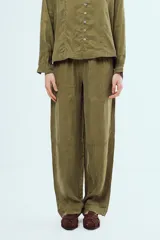 Pantalón largo negro de corte holgado y tiro medio, con costuras visibles en color blanco que delinean su diseño y bolsillos.