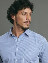 Camisa de vestir de manga larga con diseño de rayas verticales finas en color celeste y blanco. Presenta cuello clásico, cierre frontal con botones y un bolsillo en el pecho.