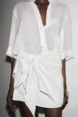 Camisa de color mostaza, con cuello solapa, manga corta y bajo recto. Cierre frontal con botones.