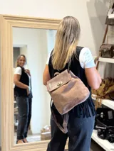 Mochila de cuero con textura tipo cocodrilo, color marrón. Cuenta con cierre de solapa con broche giratorio metálico, correas ajustables y asa superior.