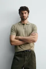 Polo de punto negro, manga corta, con cuello solapa y cierre frontal de tres botones. Presenta un calce regular y acabados en rib en mangas y ruedo.