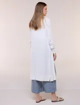 Cardigan largo de punto liviano y suave, de color blanco, con diseño abierto al frente, mangas largas con puños acanalados y bolsillos frontales aplicados.