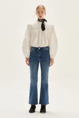 Jean de mezclilla azul de tiro medio, con silueta ligeramente acampanada desde la rodilla.