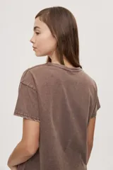 Remera de manga corta y cuello redondo color gris con efecto lavado, calce relajado y detalles de strass aplicados en la parte superior.