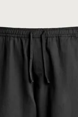 Pantalón de corte relajado confeccionado en una mezcla de algodón y lino. Presenta cintura elástica con cordón ajustable, bolsillos laterales y bolsillos traseros de vivo.