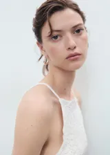 Top blanco sin mangas, con tirantes finos, cuello halter y detalle de aplique de crochet en la parte frontal. Diseño entallado.