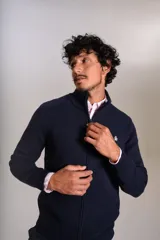 Cardigan de punto color azul marino, con cuello alto, cierre frontal completo y puños acanalados. Presenta el logo de la marca bordado en el pecho.
