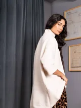 Polerón negro de tejido de punto con cuello alto, diseño oversized, mangas 3/4 y corte asimétrico más largo en la parte posterior.