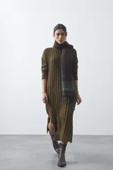 Vestido midi de punto en color gris, con diseño de tejido acanalado vertical, cuello redondo y mangas largas. Presenta una silueta recta y fluida.