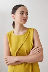 Vestido midi acampanado color mostaza, sin mangas, confeccionado en lino con detalle desflecado en los bordes. Incluye una bufanda del mismo material y color.