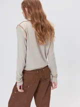 Polera de manga larga confeccionada en tela rib color bordó, con cuello alto y hombreras. Presenta costuras a la vista con pespuntes en hilo de color contrastante en el cuello, puños, hombros y ruedo.