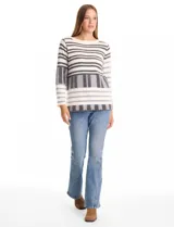 Buzo de tejido con textura ultrasuave, diseño de rayas horizontales y bloques geométricos en tonos blanco, gris y negro. Presenta cuello redondo, manga larga y un calce cómodo y holgado.