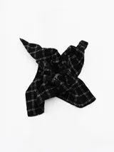 Colita de pelo tipo scrunchie de tela negra con estampado de cuadros blancos.