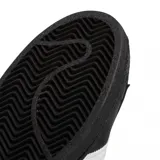 Championes Adidas modelo Superstar ADV, de diseño clásico con exterior de cuero negro, las icónicas tres tiras laterales en blanco y la característica puntera de goma. Incluye el logo Superstar en dorado en el lateral y el logo de la marca en la lengüeta y el talón.