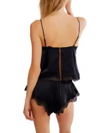 Conjunto de ropa de descanso de dos piezas, color negro, compuesto por un camisola con tirantes finos y un short. Ambas piezas son de encaje floral transparente y tienen detalles de ribete festoneado.