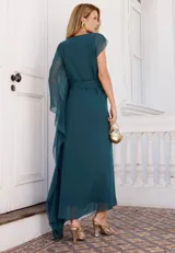 Vestido largo de fiesta color verde petróleo, confeccionado en tela fluida con transparencias. Presenta un diseño de un solo hombro con manga larga tipo capa, ajuste en la cintura con lazo lateral y falda con caída suave.