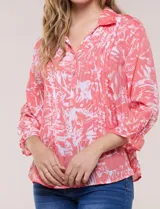 Blusa celeste con estampado efecto pincelada blanca, de corte semi holgado, escote en V con cuello solapa y media abotonadura frontal con botones nacarados. Presenta finas alforzas verticales en la pechera y mangas 3/4 con puños elastizados.