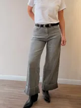 Jeans palazzo de corte ancho, color gris, tiro medio y botamanga con dobladillo ancho fijo. Incluye cinto negro con hebilla metálica.