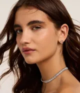 Conjunto de collar corto plateado con múltiples hileras de strass y esferas, acompañado de aros abridores con diseño de corazón calado.
