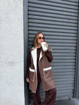 Chaleco largo de eco cuero color marrón con interior y detalles de corderito en solapas y bolsillos frontales.