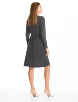 Vestido corto de seda fría con estampado botánico en blanco y negro. Presenta escote en V cruzado, mangas largas entalladas, cintura elastizada con aplique metálico lateral y ruedo asimétrico.