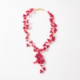 Colgante de diseño artesanal compuesto por múltiples cuentas de cristal facetado en color rojo, entrelazadas con hilo metálico dorado. Presenta una estructura flexible con un dije central colgante de mayor volumen y cierre de mosquetón.
