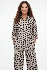 Camisa de manga larga con estampado animal print tipo leopardo, cuello camisero y cierre frontal de botones negros.
