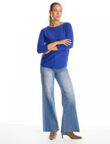 Buzo de tejido fino con cuello redondo, manga tres cuartos con puños acanalados y detalle de pespunte vertical en el frente. Presenta un diseño liso con aplique de botones en la espalda.