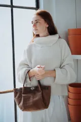 Mini bag de cuero con textura grabada, diseño estructurado y cierre metálico frontal. Cuenta con doble asa superior y correa larga desmontable.