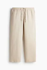 Pantalón de corte regular fit confeccionado en mezcla de lino y algodón, color beige. Presenta cintura elástica con cordón ajustable, cierre de botón y bolsillos laterales.