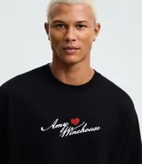 Remera boxy fit de algodón color negro, con cuello redondo y mangas cortas. Presenta un estampado de la cantante Amy Winehouse en blanco y negro con detalles en rojo, y la inscripción "Amy Winehouse Back to Black".