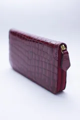 Billetera rectangular con cierre perimetral, confeccionada en cuero con textura de reptil. Cuenta con múltiples compartimentos internos para tarjetas, documentos y billetes, además de un bolsillo interior con cierre para monedas.