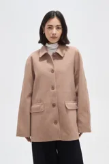 Tapado de paño color beige, con cuello camisero, cierre frontal de botones y bolsillos laterales con solapa.