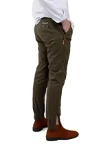 Pantalón de vestir verde oliva, de corte recto, con bolsillos laterales y traseros. Se ajusta a la cintura con cinturón de cuero marrón. Presenta un tajo con botones en el tobillo.