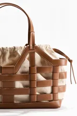 Bolso tipo tote grande de tela revestida marrón con estructura exterior trenzada imitando cuero y bolsa interior de lona de algodón y lino con cordón ajustable.