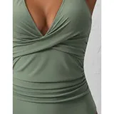 Malla entera de color verde oscuro, combinada con un diseño floreado en la parte inferior. Presenta escote halter cruzado y fruncidos en la zona del abdomen.
