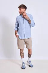 Camisa de corte regular con diseño de rayas verticales finas en tonos claros, cuello clásico y mangas largas con puños abotonados.