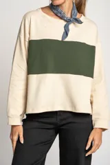 Sweater color crema con una franja horizontal verde en el pecho, de corte oversize y mangas largas.
