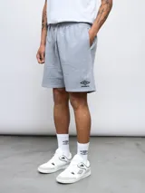 Bermuda de felpa Umbro color gris melange, de corte relajado, con cintura elástica con cordón de ajuste y bolsillos laterales. Cuenta con el logo de la marca bordado en negro en la pierna izquierda.