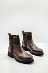 Botas de cuero color marrón con detalles de textura de cocodrilo en los laterales y la parte superior. Tienen cierre lateral y suela robusta negra.