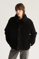 Campera negra de sherpa con cuello camisero, cierre con botones a presión y calce estándar.