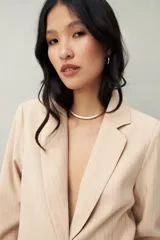 Blazer color crema a rayas verticales finas, de corte recto y solapas clásicas.